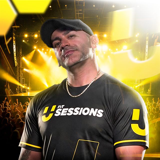 Mário Lopes de boné preto e camiseta preta do UFit Sessions, com o palco iluminado ao fundo